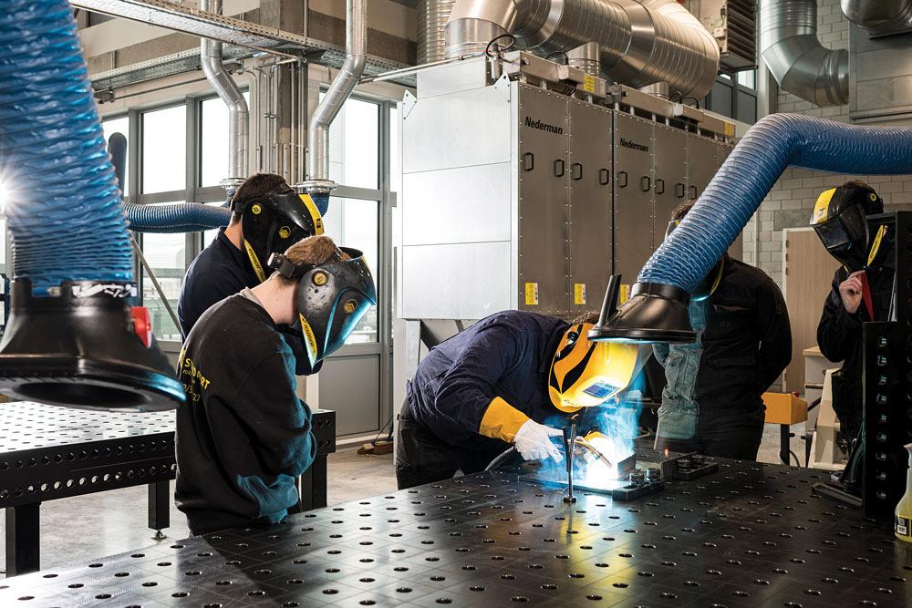 Welders weld on a table and use fume extraction system to remove weld fumes at the source.