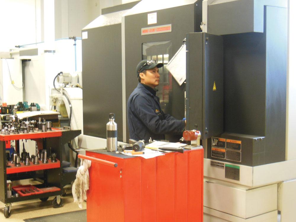 老虎工具的一名工人检查在森精木双立式5100轧机上加工的一个零件的进度。