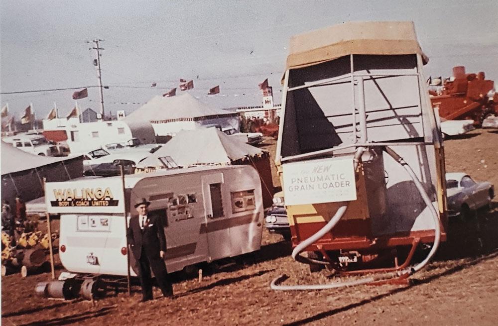 Company founder Case Walinga stands in front of a trailer and beside some farm machinery.