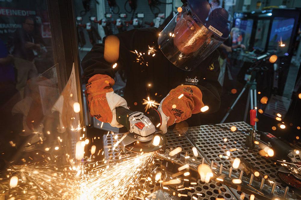 An operator grinds a piece of metal with an angle grinder. 