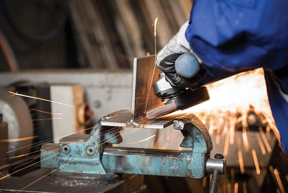 An operator grinds a part on a vise.