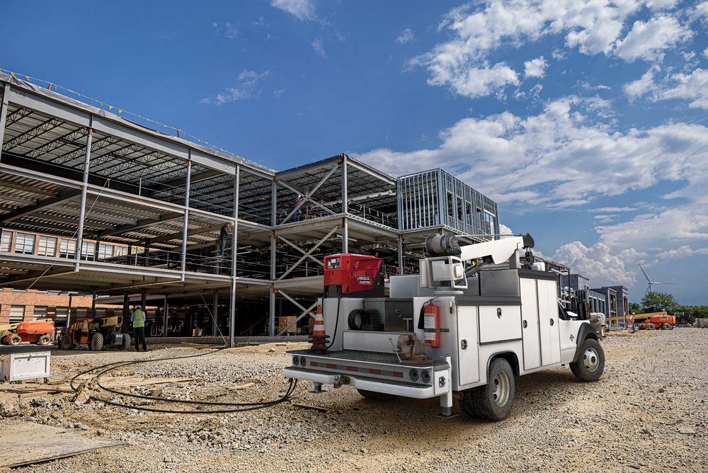 Mobile welding rig parked at a construction site with steel framework, showcasing on-site welding capabilities for efficient repairs and fabrication.