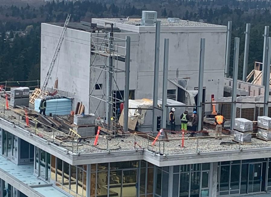 Metal fabricators and welders work on the top of a high-rise building.