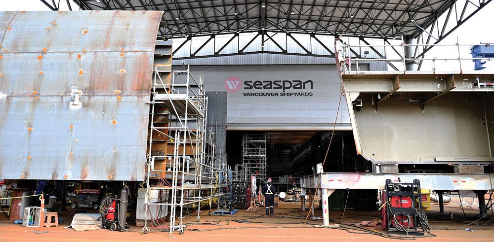 The Seaspan logo is seen in the background between two partially-built structures. A welding machine sits in the right foreground. 