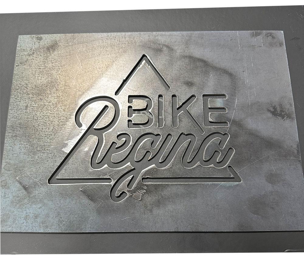 A metal plate that has the words “Bike Regina” sits on a table. 