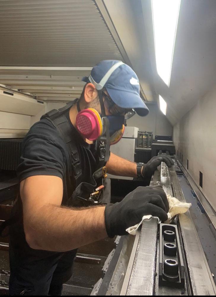 A technician is seen cleaning and lubricating linear guide rails. 