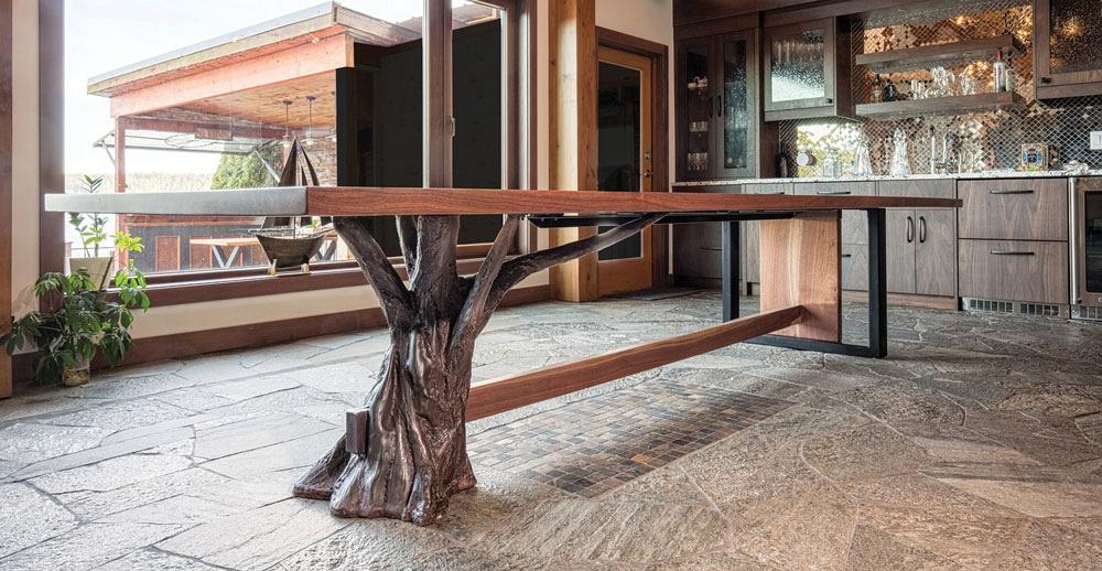 A view of a walnut-topped dining room table supported by metal that has been worked to look like a tree stump.