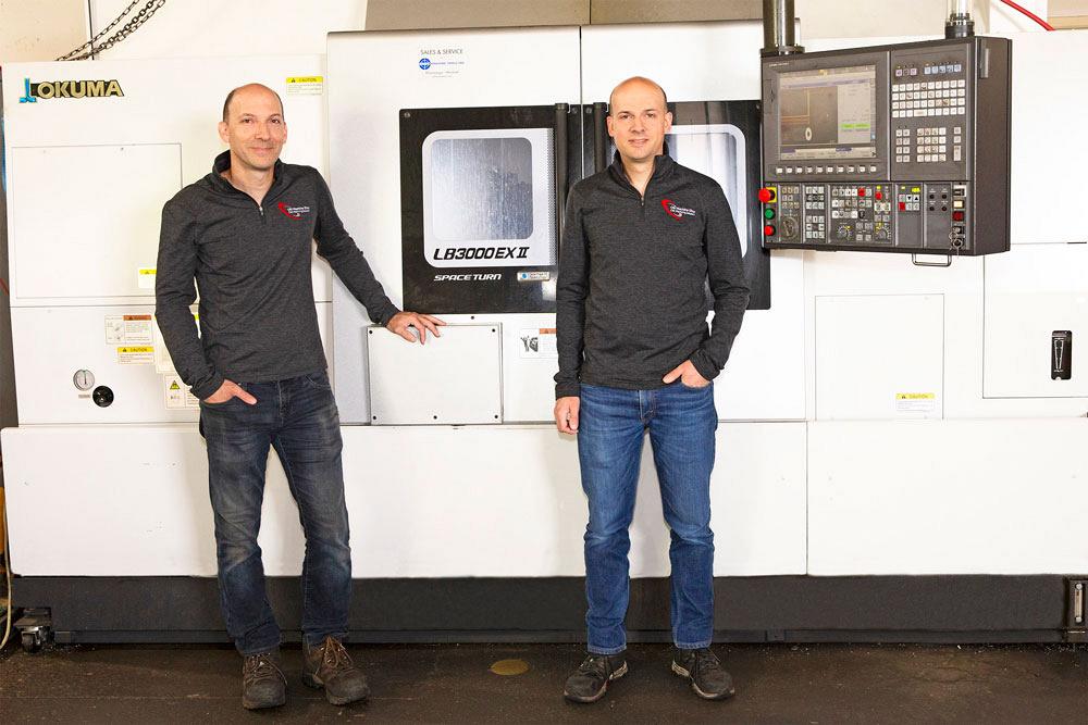 Ran and Shai Ofir stand in front of their Okuma LB3000 EX II MY horizontal lathe