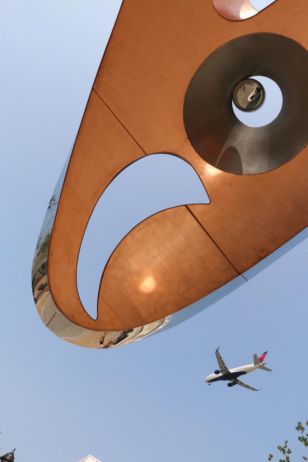Sei sculpture watches plane pass overhead at Vancouver Airport.