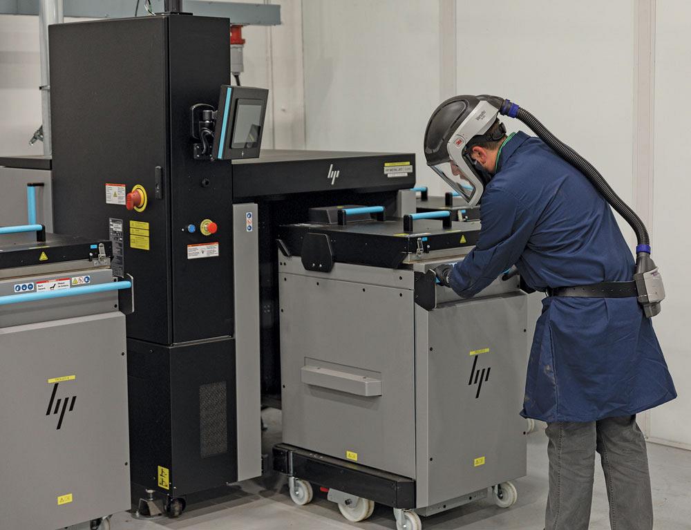 A worker loads an additive manufacturing machine.