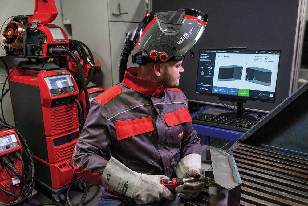 A welder looks at data on a screen between operations. 