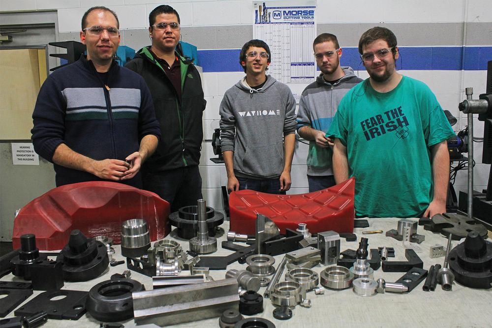 Students stand by parts made in the CMTS training program.