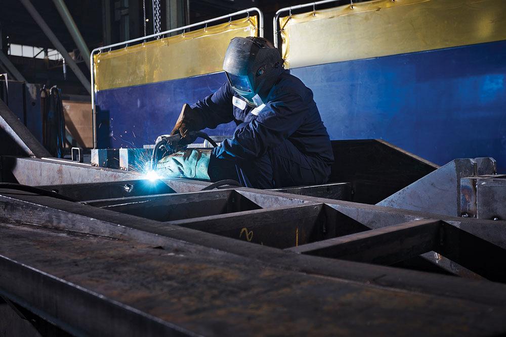 A welder works on a large weldment at Norwest Precision