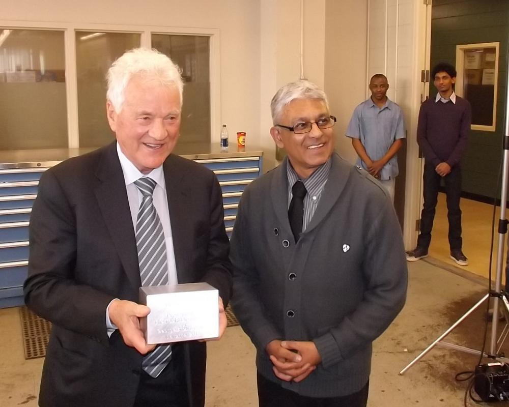 Frank Stronach is presented with an engraved aluminum cube Pradeep Kalsi, Professor, Centre for Construction &amp; Engineering Technologies, at George Brown's Casa Loma campus in Toronto. (Photo: Jim Anderton/Canadian Metalworking)