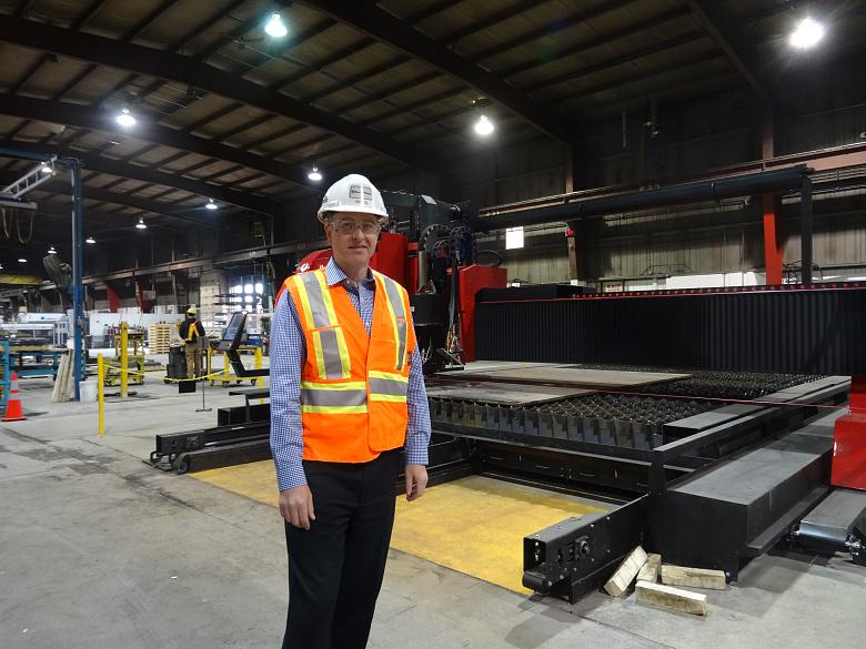 Greg Ozog, branch manager of the Russel Metal&rsquo;s Winnipeg facility,
stands in front of the company&rsquo;s new machine, a Kinetic K5000xmc
multi-functional cutting and drilling machine.