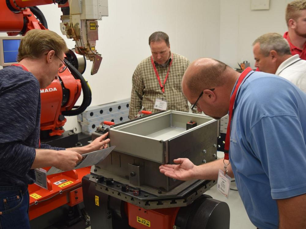 Attendees of Amada's Innovation Expo examine a weld completed on the FLW 4000 fiber laser welding system. 