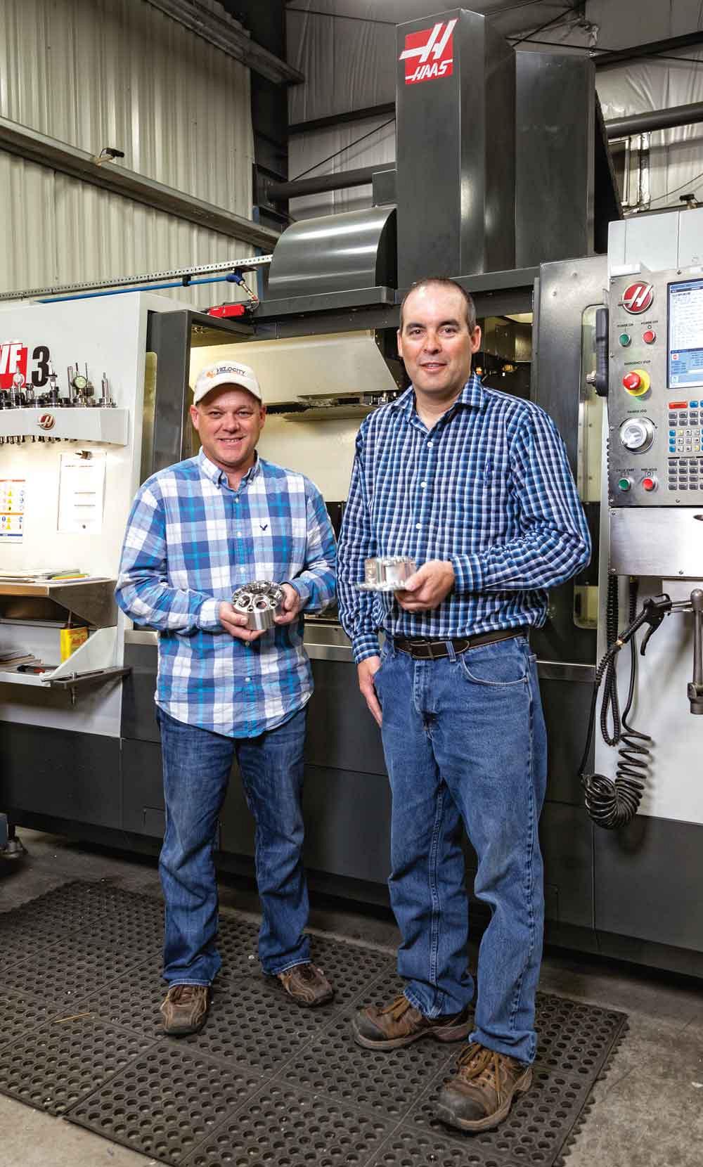 Craig Langille (left), vice president, and Sean MacPhee, president, of Techtronics Machine Works and Velocity Machining & Welding in Nova Scotia hold work samples in front of one of TMW’s Haas 5-axis machining centres.