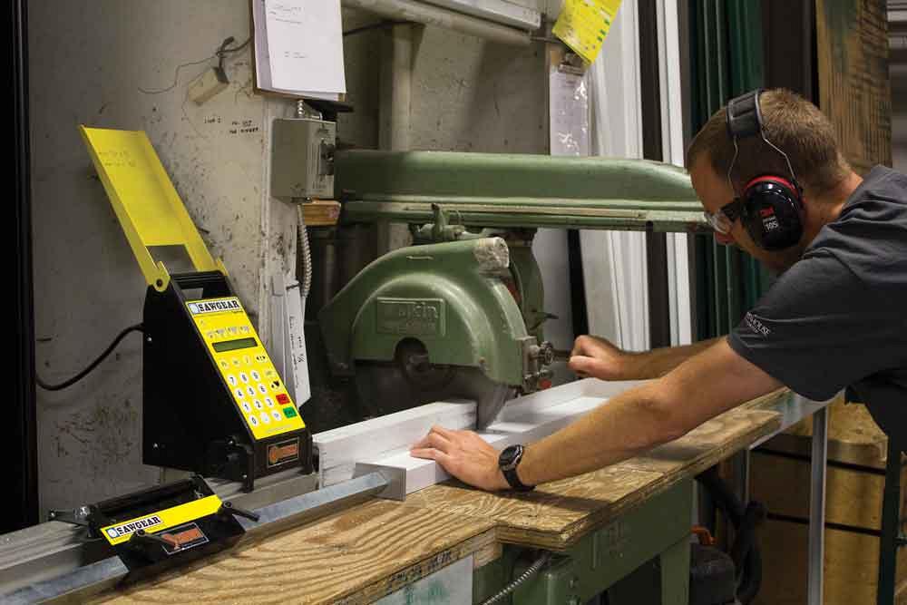Brent Hoogland cuts greenhouse trusses from 1 ½- by 3- by ¼-in. channel using a 14-in. Wadkin radial arm saw. The company’s second SawGear system, an SG08, positions the material.